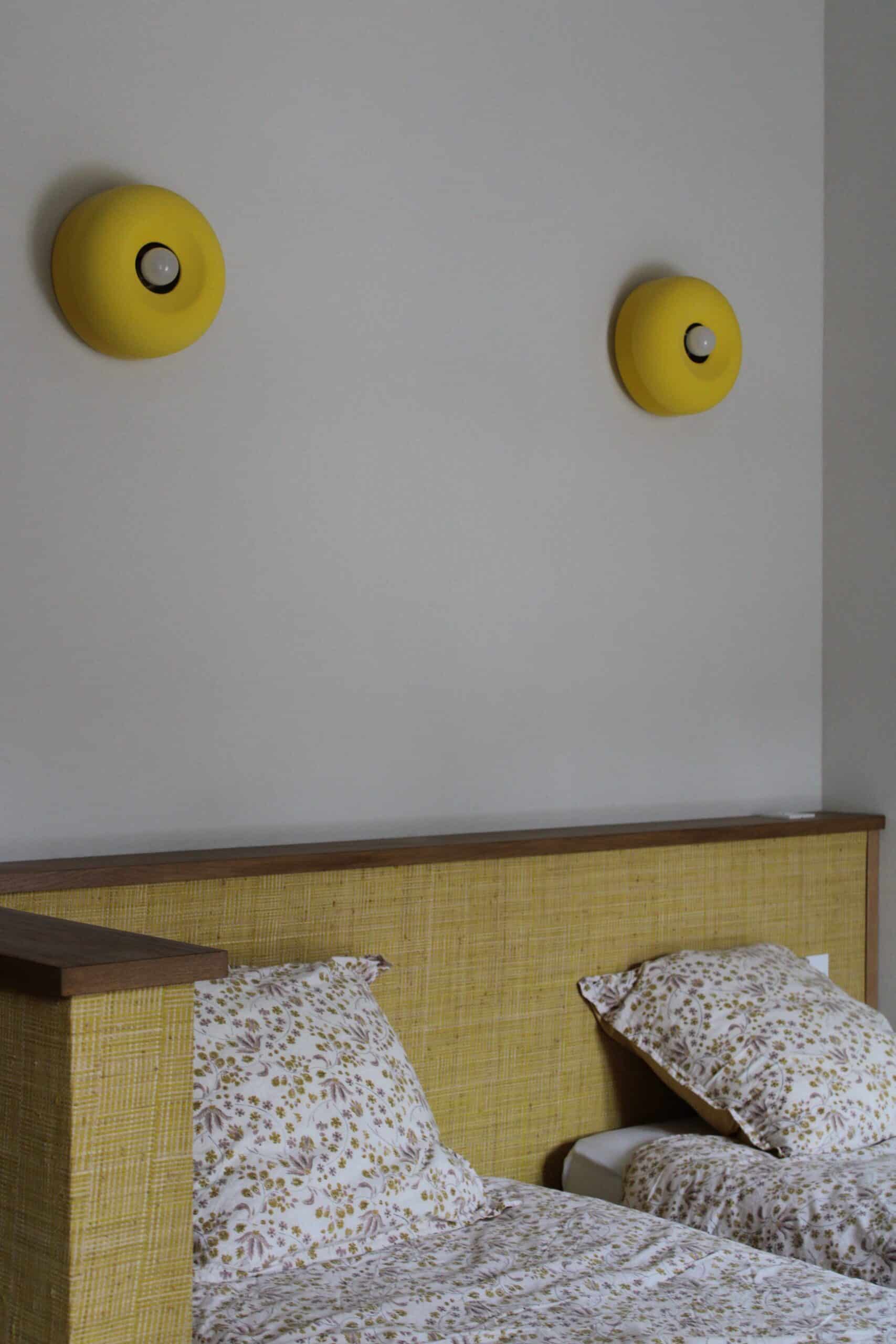 Appliques rondes jaunes et tête de lit texturée jaune avec literie à fleurs.