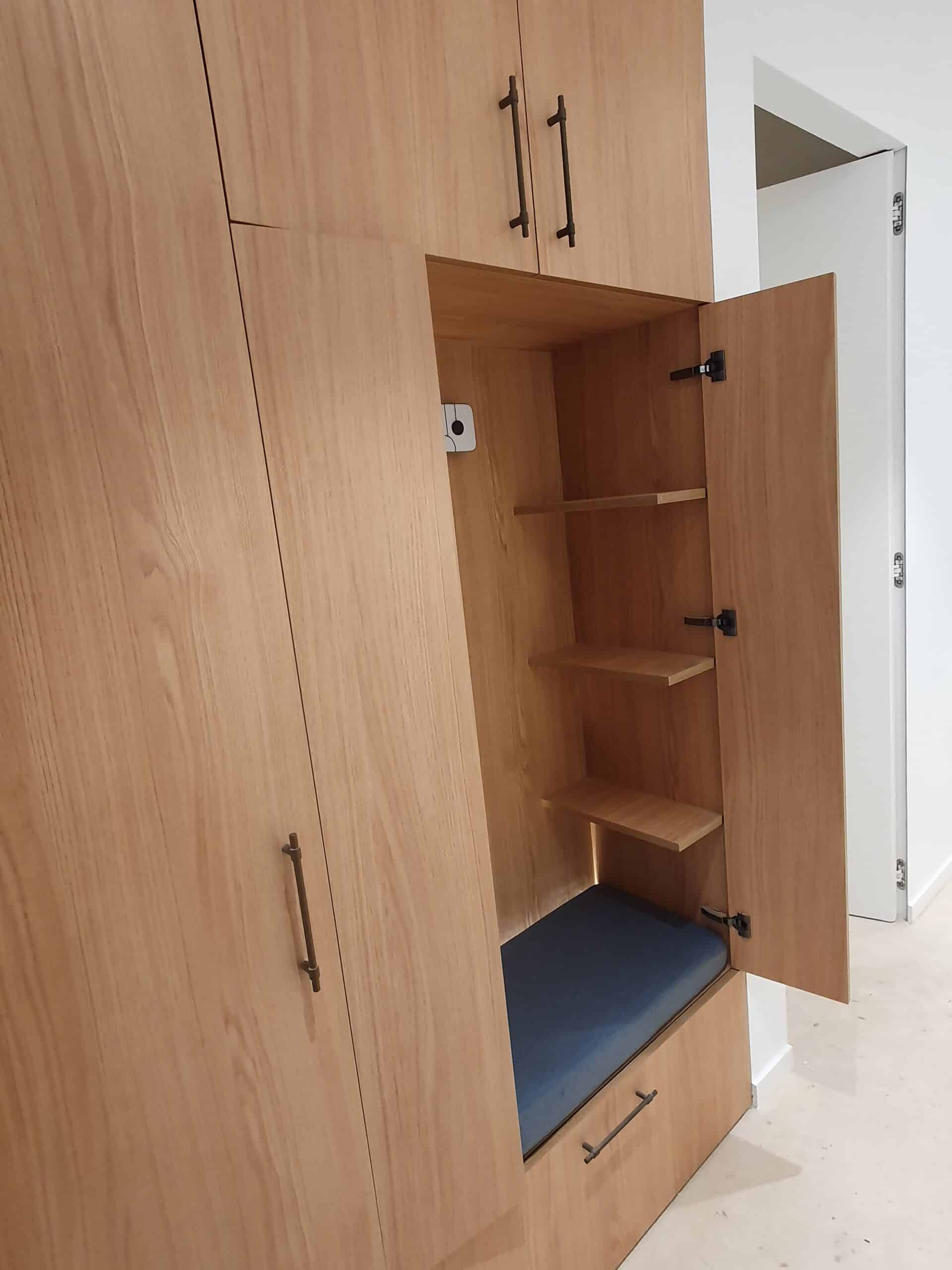 Armoire en bois clair avec banquette bleue et étagères.