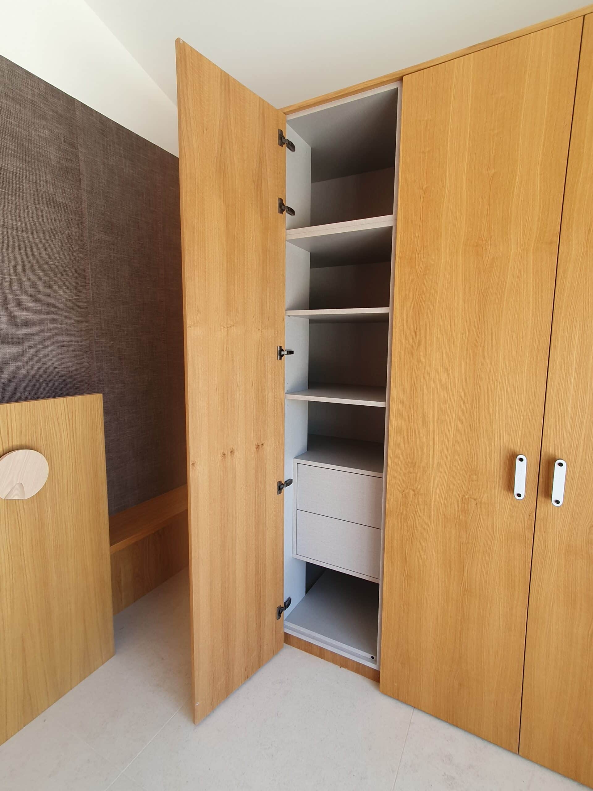 Armoire en bois clair ouverte révélant étagères et tiroirs intérieurs blancs.