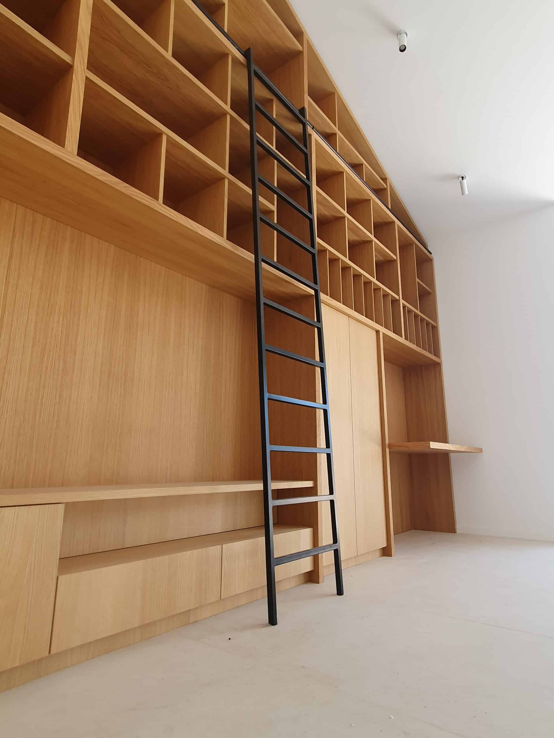 Bibliothèque en bois clair sur mesure avec échelle noire minimaliste dans une pièce lumineuse.