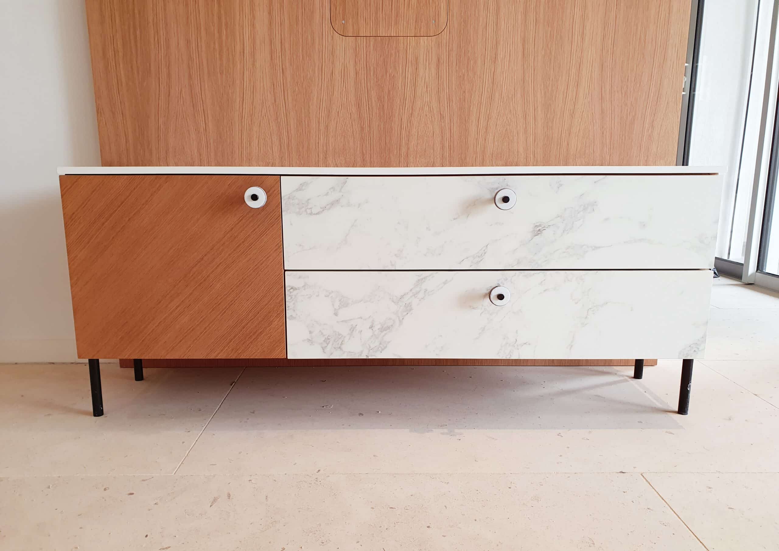 Buffet design : porte bois clair, tiroirs marbrés blancs et pieds noirs.