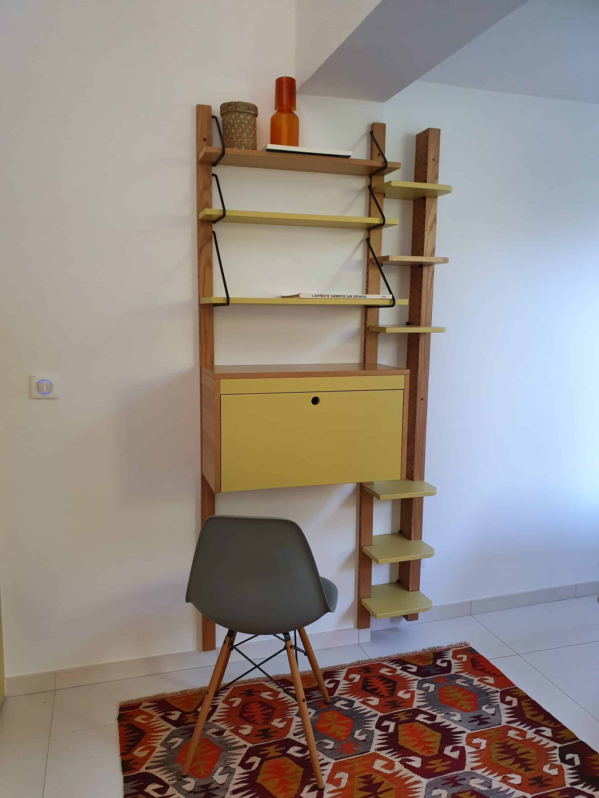 Étagère bois, bureau jaune, chaise grise et livre L'Antiquité racontée aux enfants sur tapis coloré.