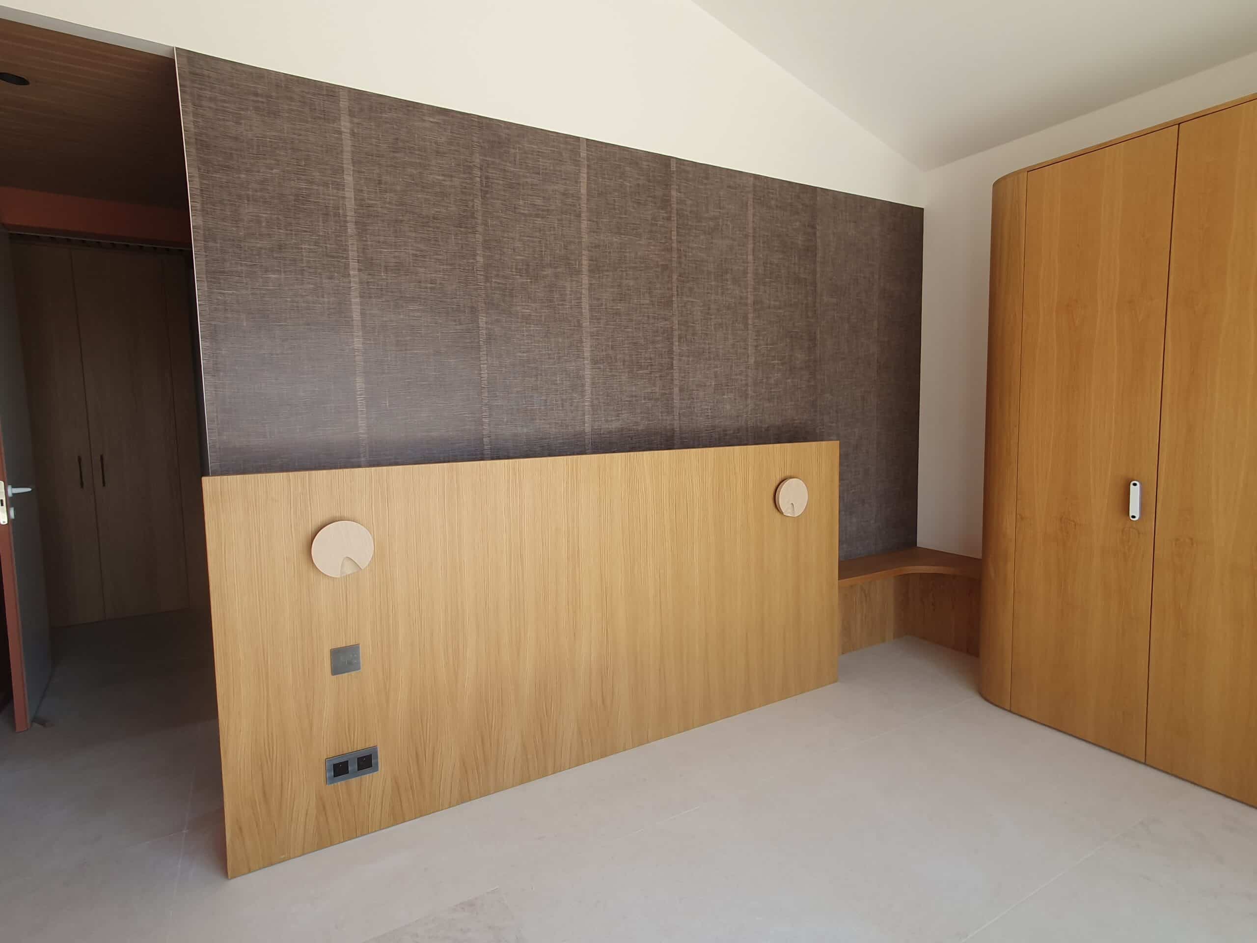 Tête de lit en bois avec appliques rondes et armoire assortie dans une chambre moderne.