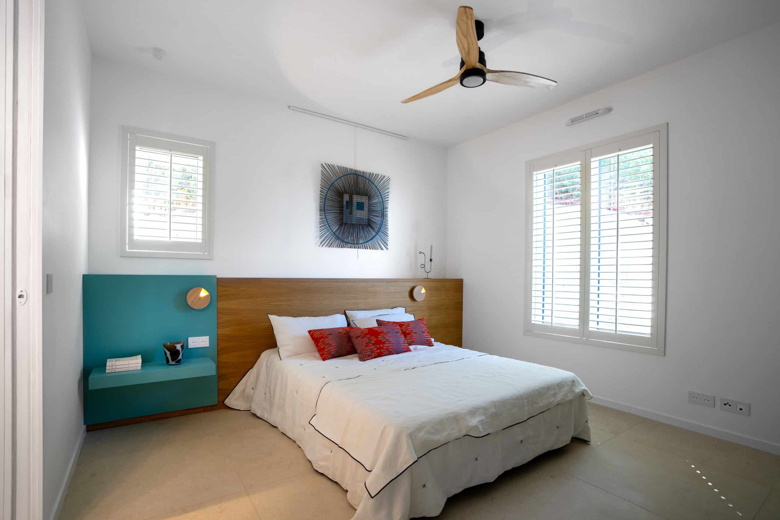Chambre minimaliste avec lit blanc, tête de lit en bois et étagère turquoise intégrée.