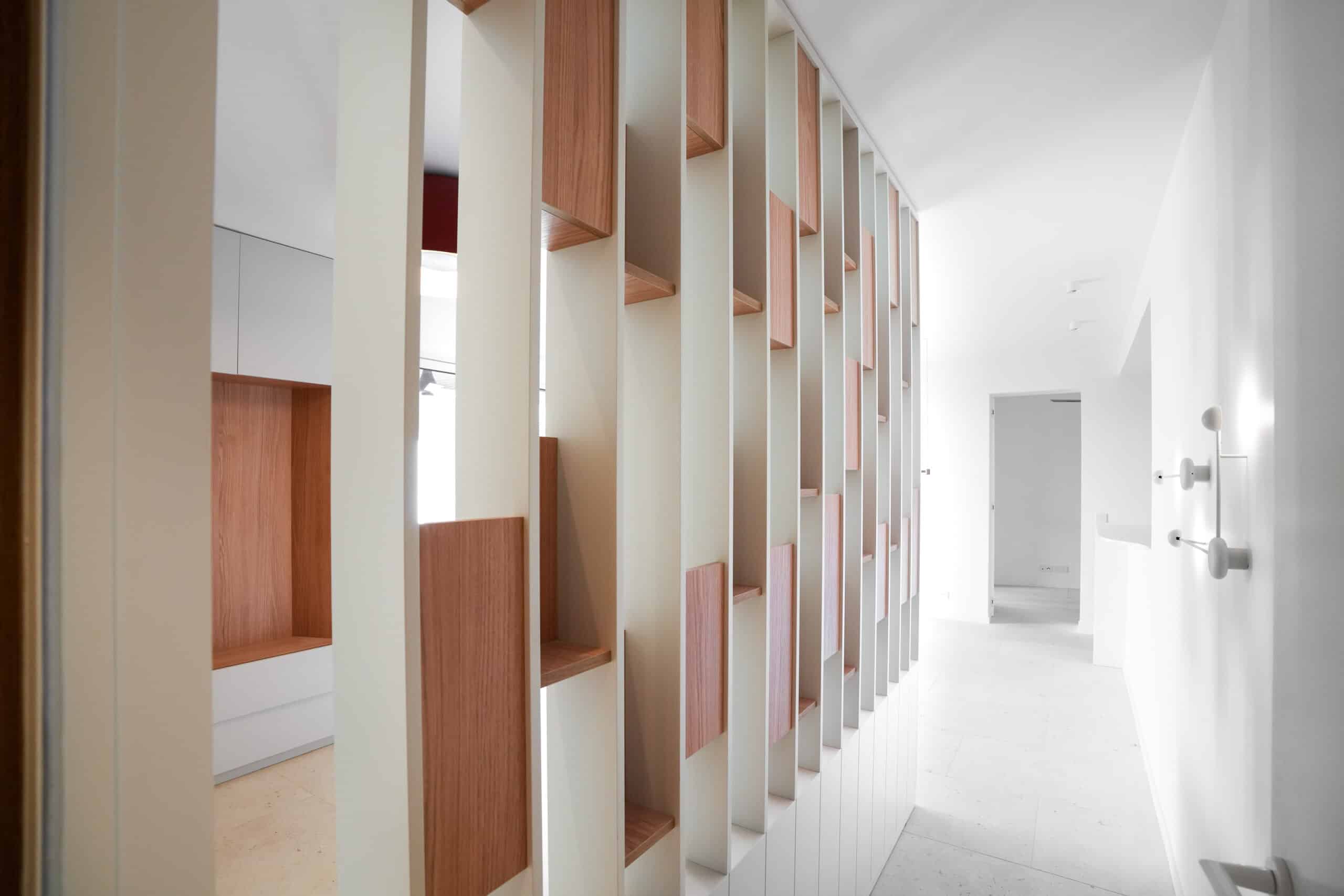 Cloison ajourée en bois et blanc dans un couloir minimaliste moderne et lumineux.