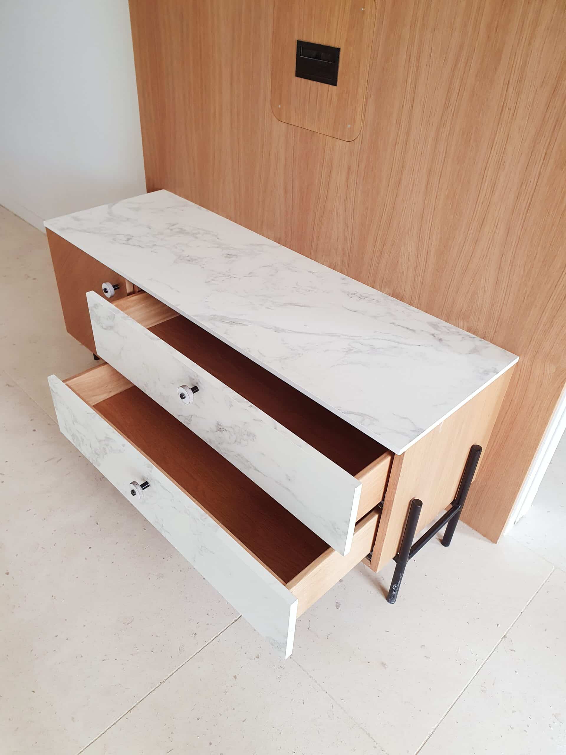 Commode moderne en bois avec plateau et tiroirs aspect marbre blanc, pieds noirs en métal.
