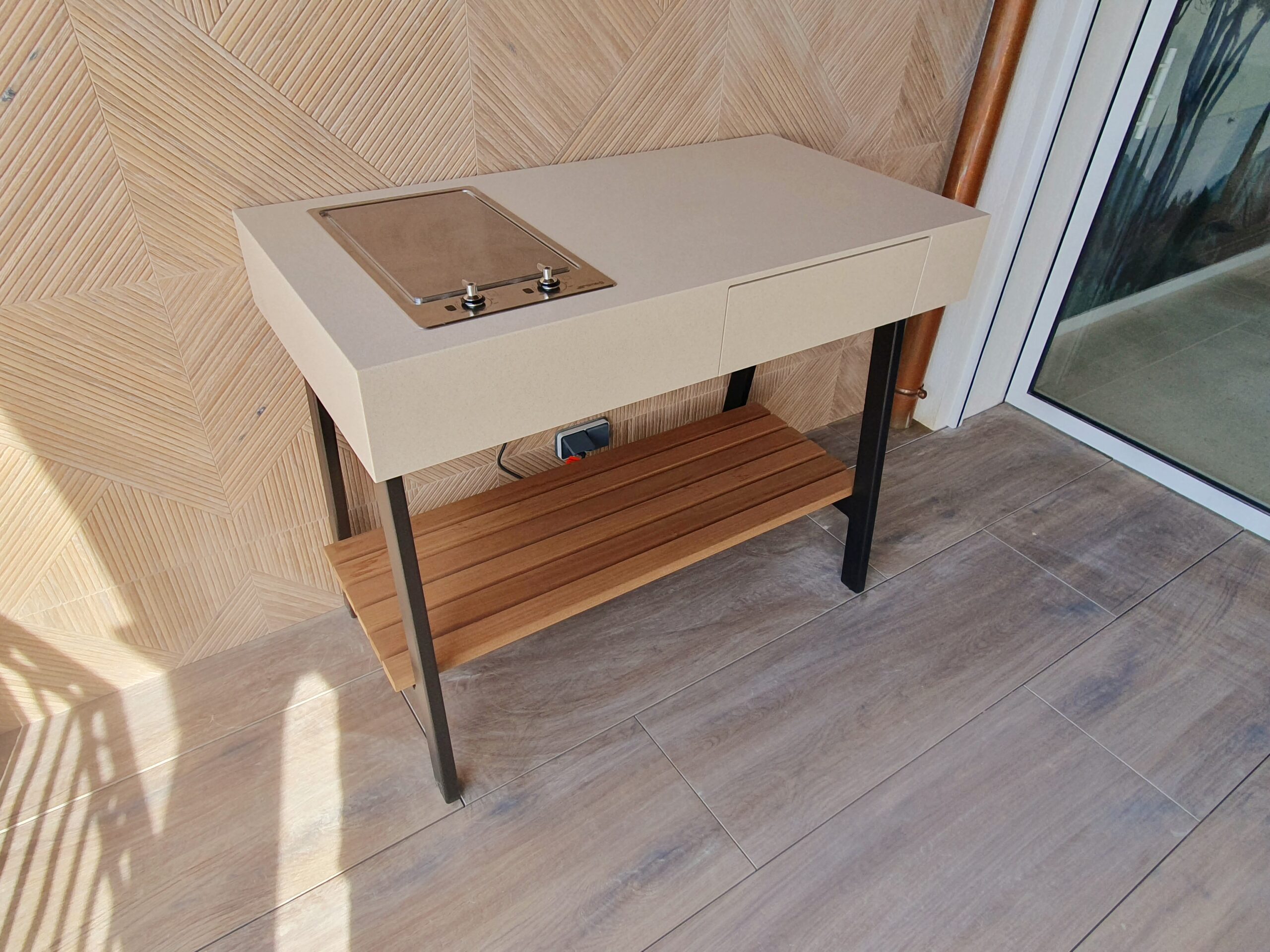 Cuisine d'extérieur moderne avec plaque de cuisson Smeg intégrée, étagère en bois et cadre métallique noir.