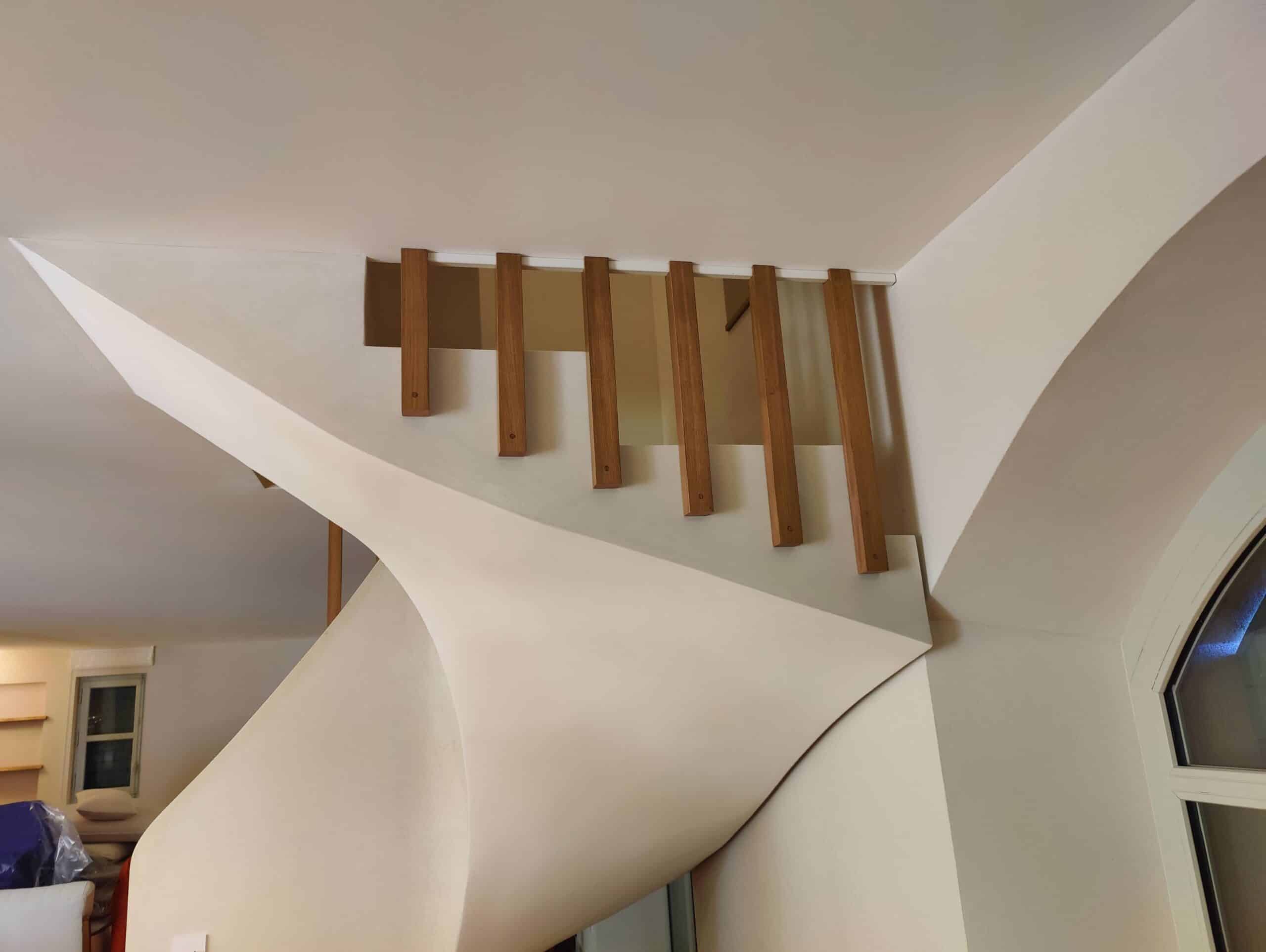 Escalier en colimaçon design blanc aux courbes fluides et garde-corps à lattes de bois verticales.