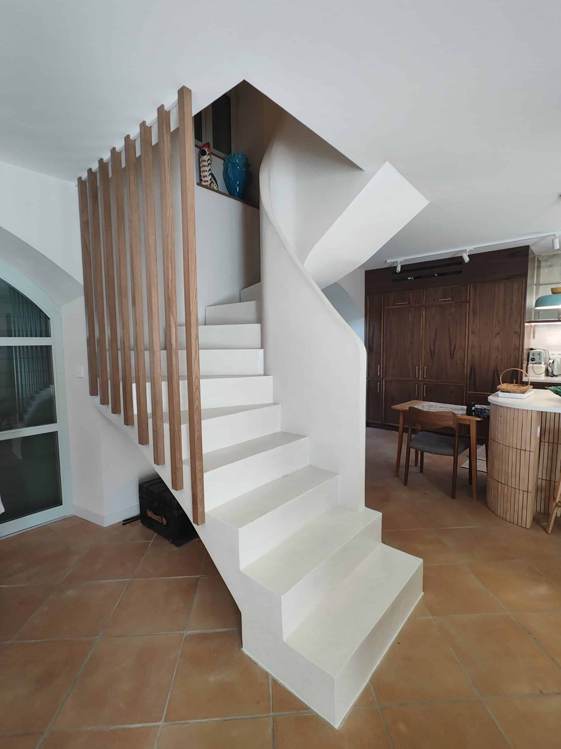 Escalier blanc sculptural avec garde-corps en lattes de bois clair sur sol en tomette moderne.