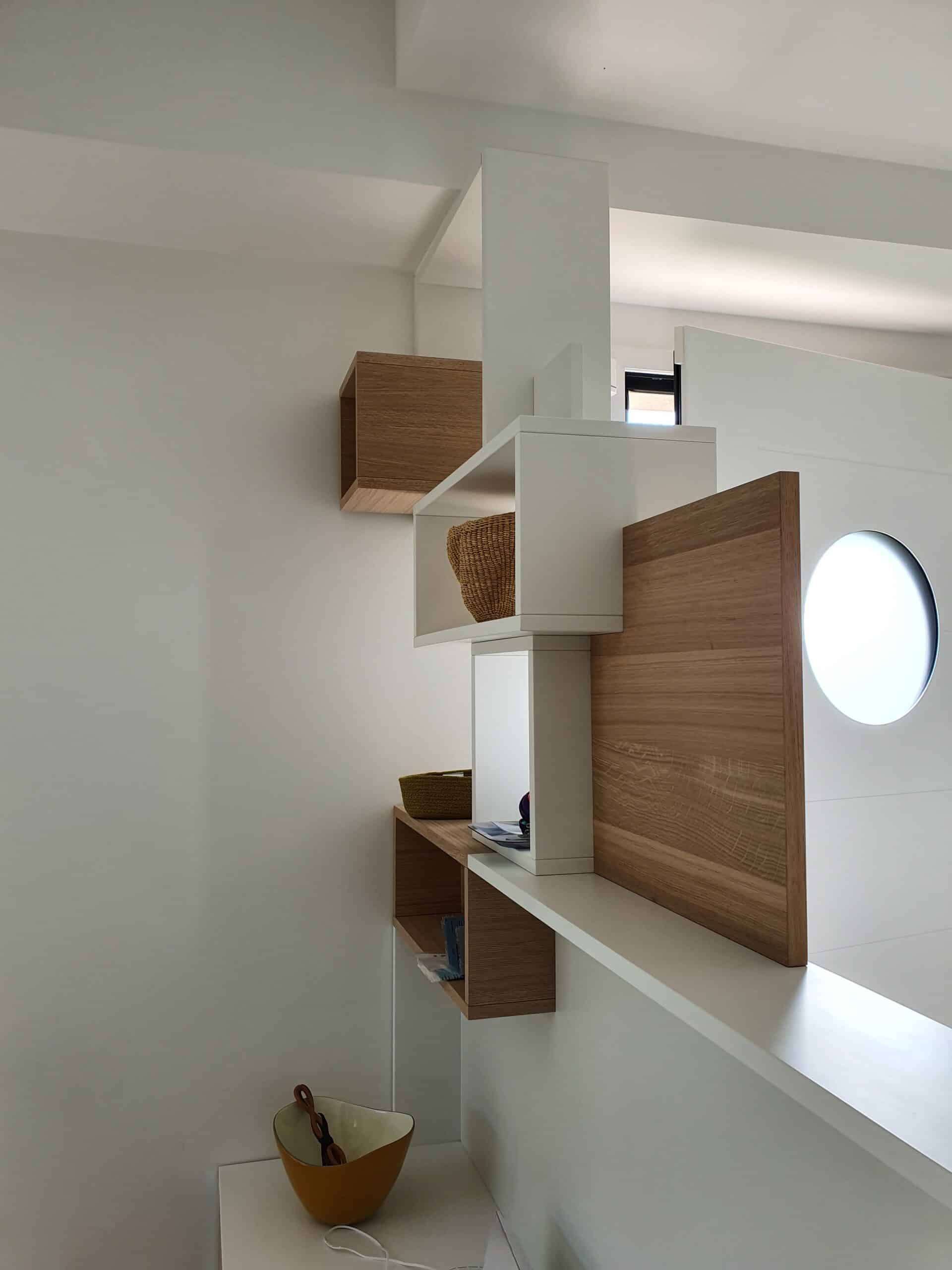 Étagère murale minimaliste en bois et blanc avec hublot lumineux et paniers décoratifs.