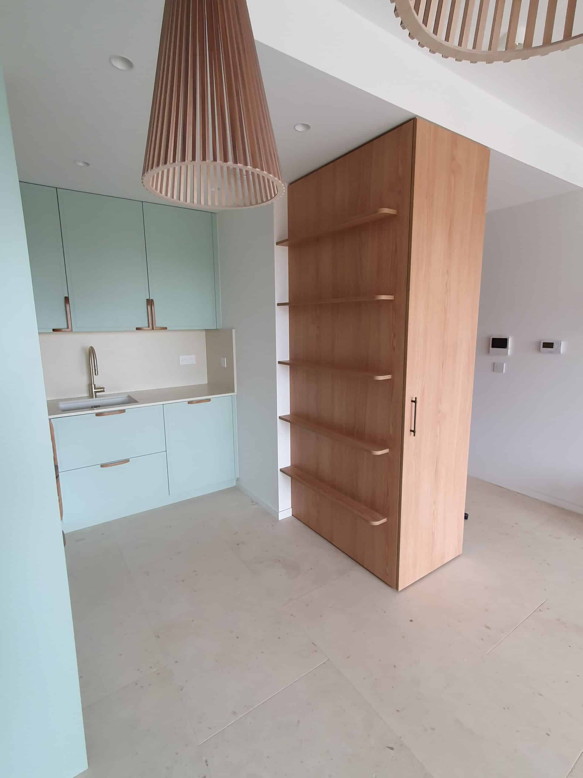 Kitchenette moderne bleu pâle avec évier et meuble de rangement mural en bois clair.