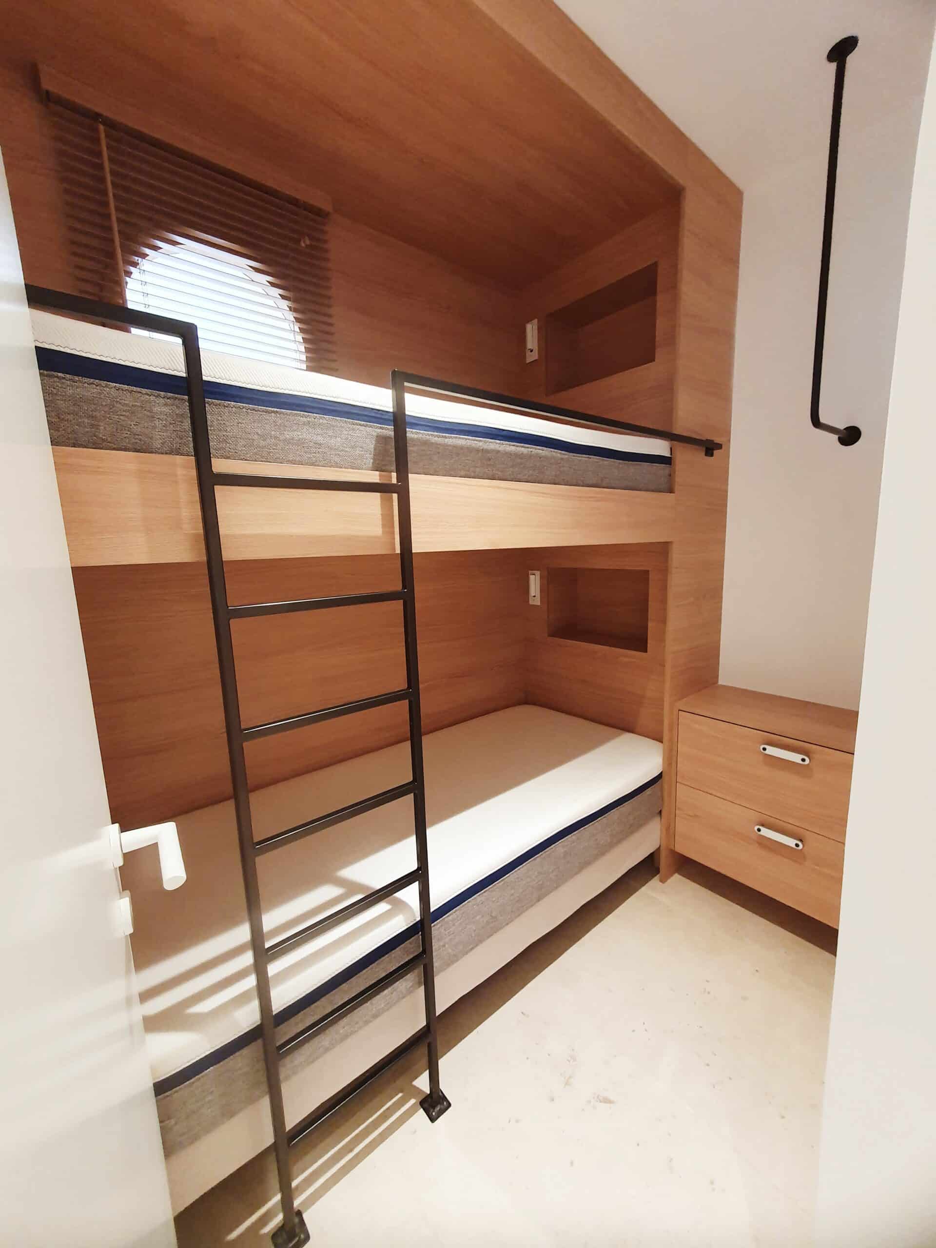 Lit superposé en bois moderne avec échelle noire et commode dans une petite chambre optimisée.