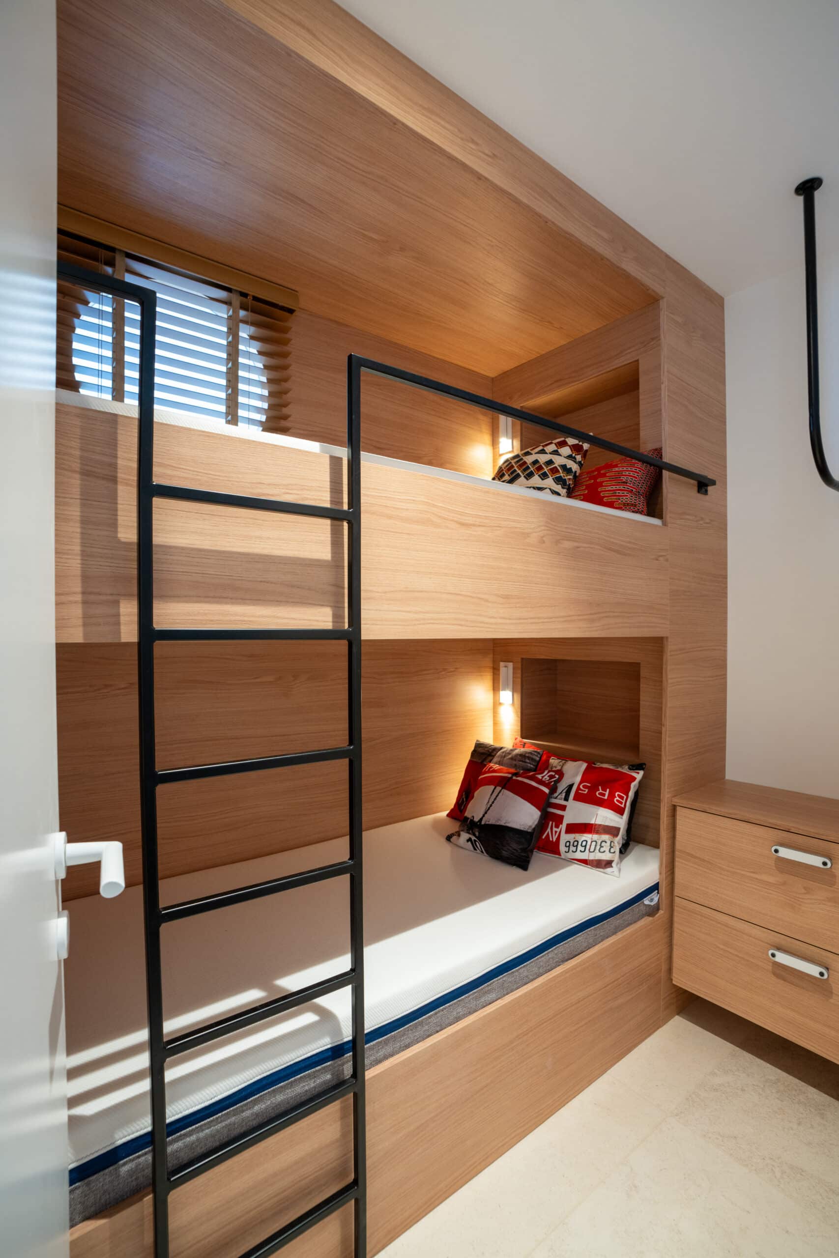 Lits superposés en bois sur mesure avec échelle noire et rangements intégrés.