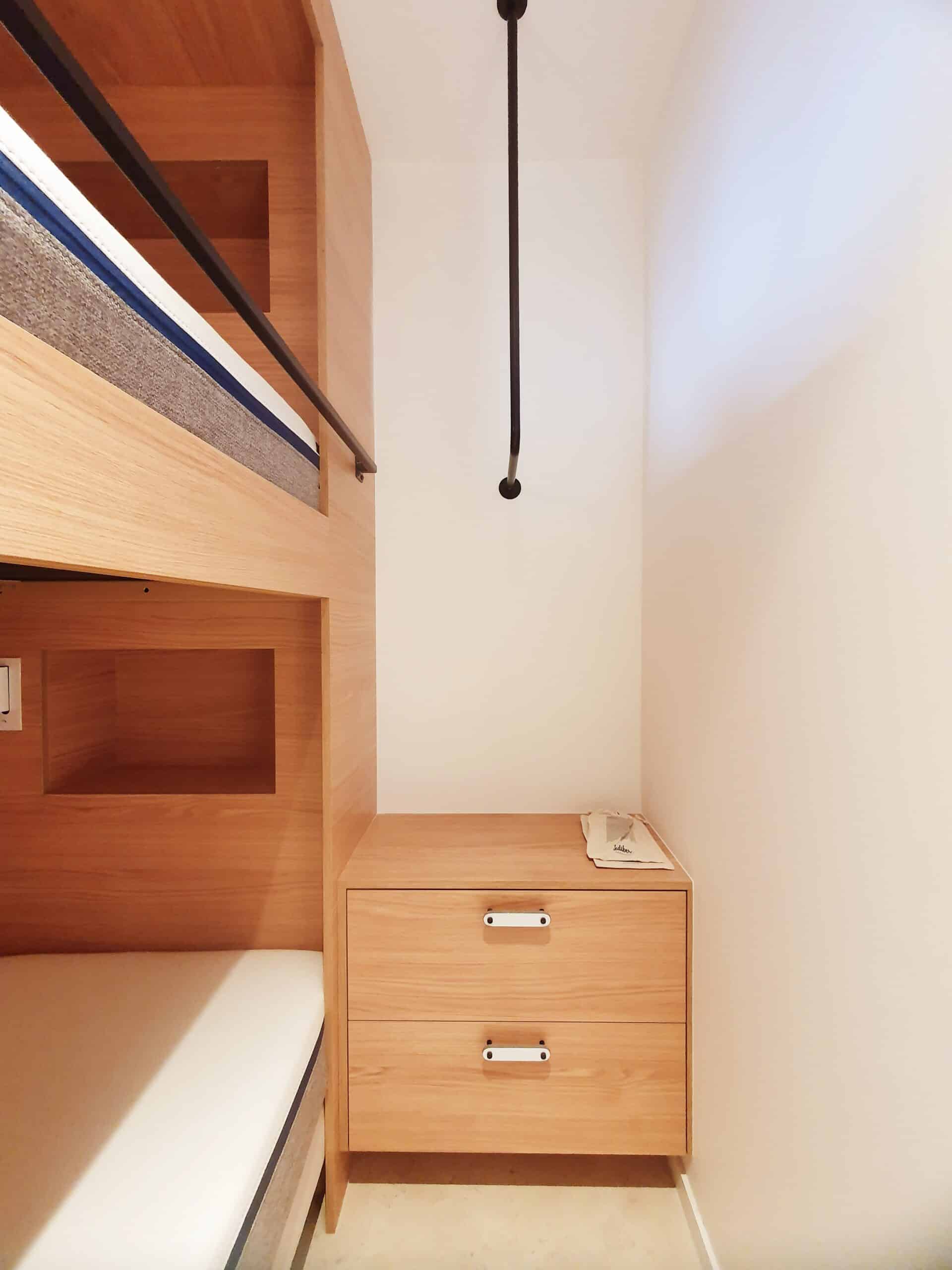 Lits superposés et commode en bois clair dans une chambre minimaliste avec tringle de penderie noire.