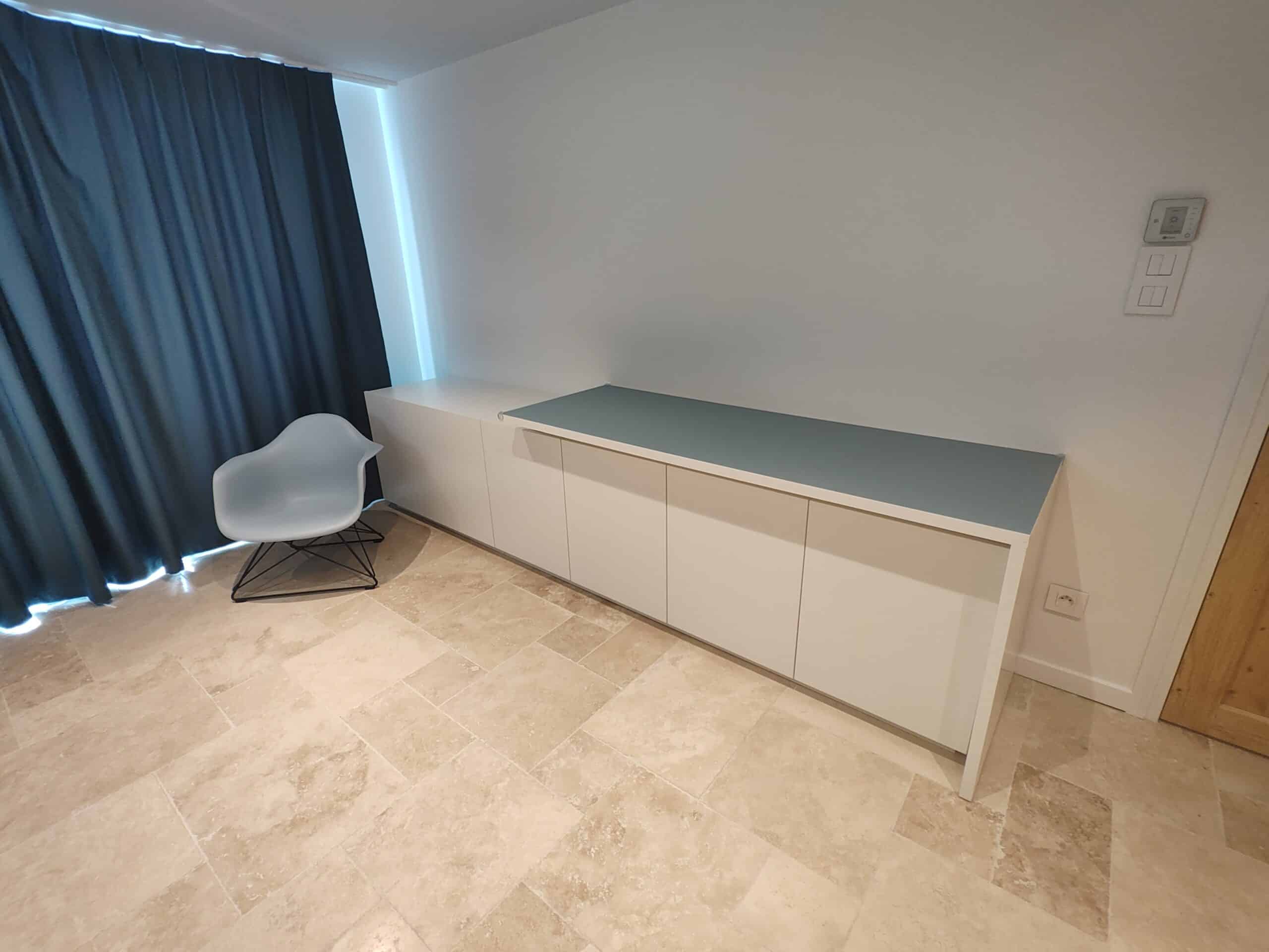 Buffet blanc design avec plateau gris, chaise bleue moderne et sol en travertin.
