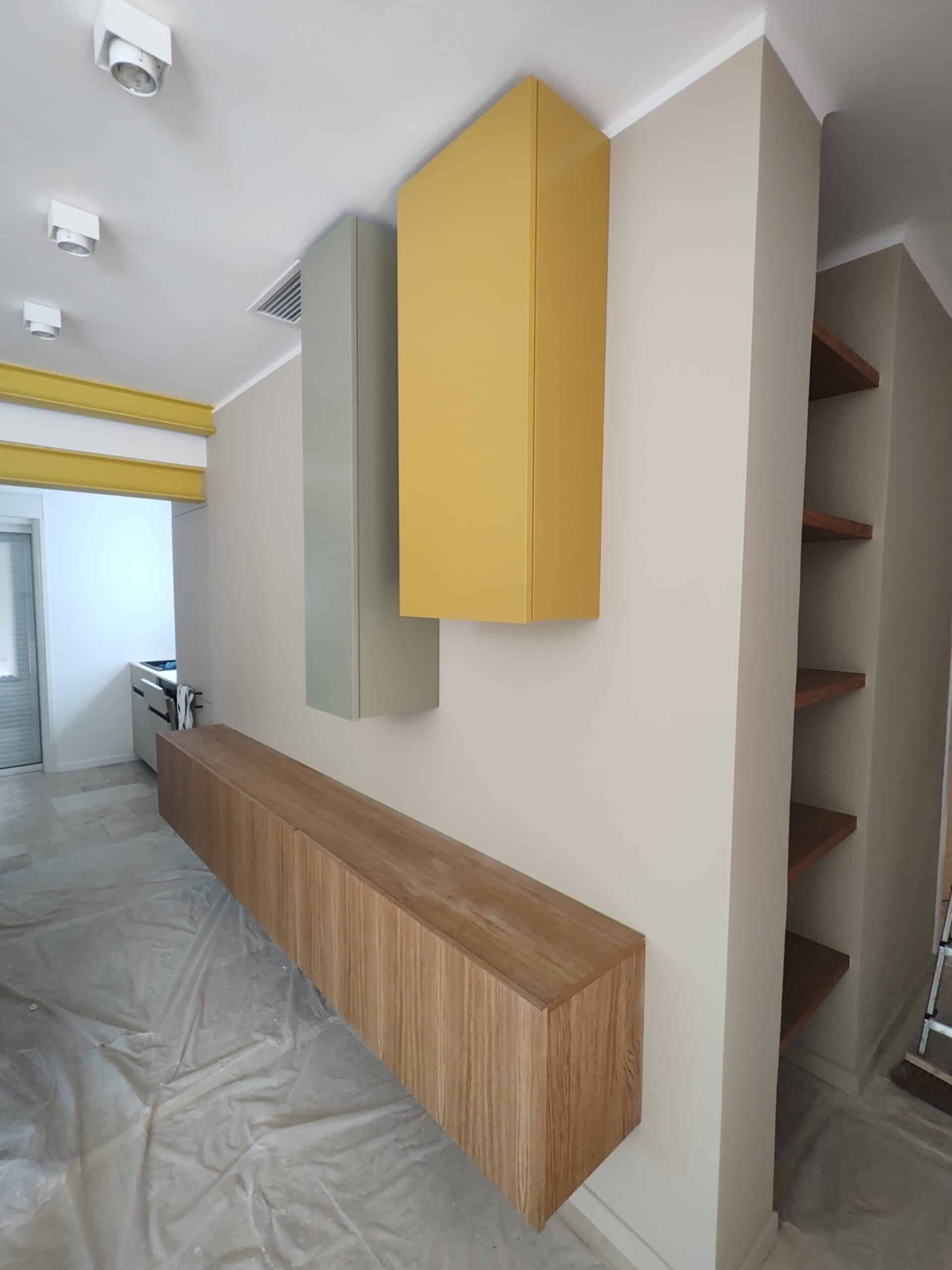 Meuble flottant en bois avec caissons jaune et vert sur mur beige, design moderne minimaliste.