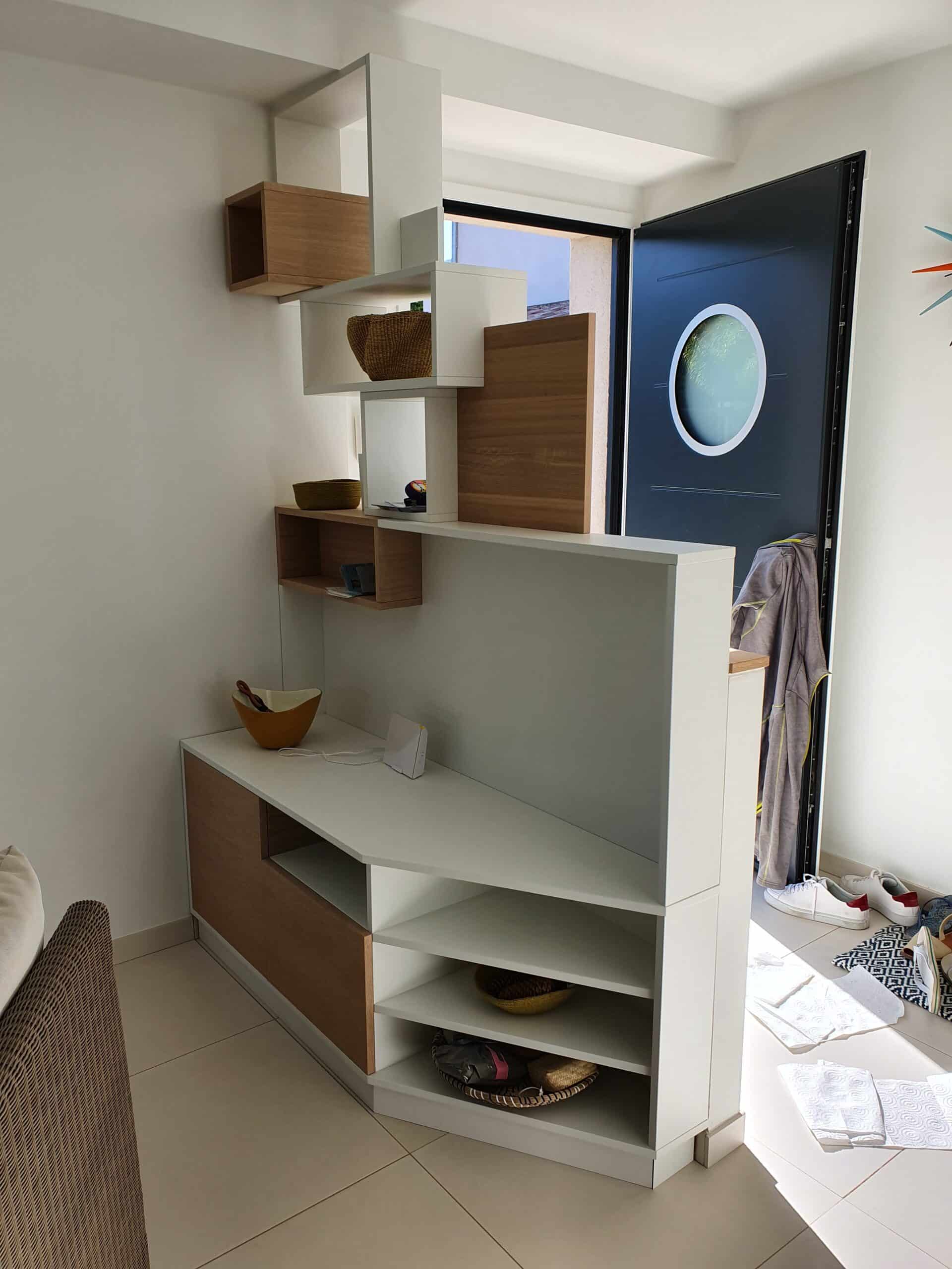 Meuble de séparation design blanc et bois dans une entrée lumineuse avec porte bleue à hublot.
