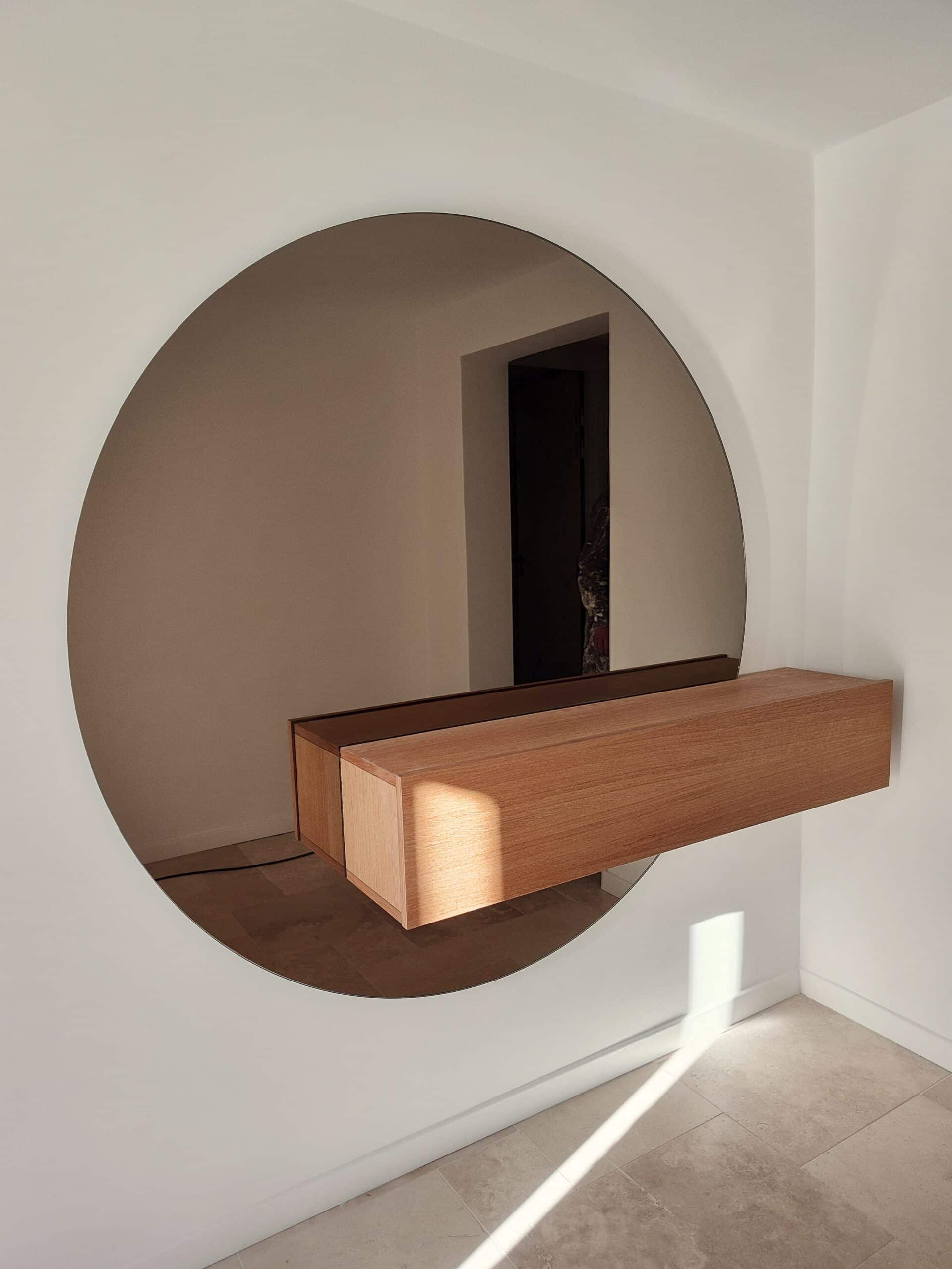 Miroir rond minimaliste et console flottante en bois clair.