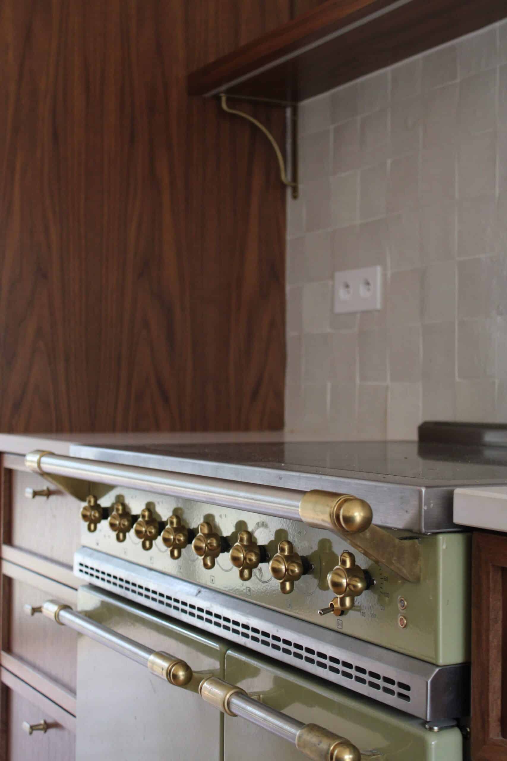 Piano de cuisson vert sauge et laiton dans une cuisine rétro chic.