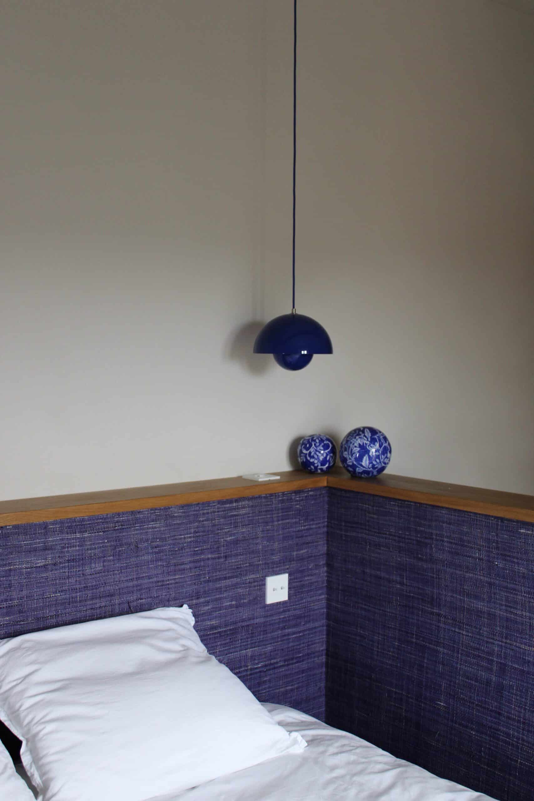 Suspension Flowerpot bleue au-dessus d'un lit avec mur violet et boules décoratives.